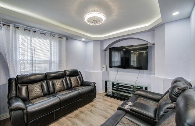 living room with a tray ceiling and light hardwood / wood-style flooring