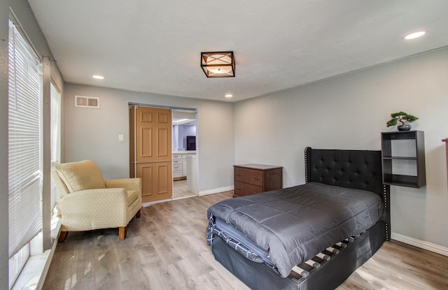 bedroom with light hardwood / wood-style flooring and a barn door