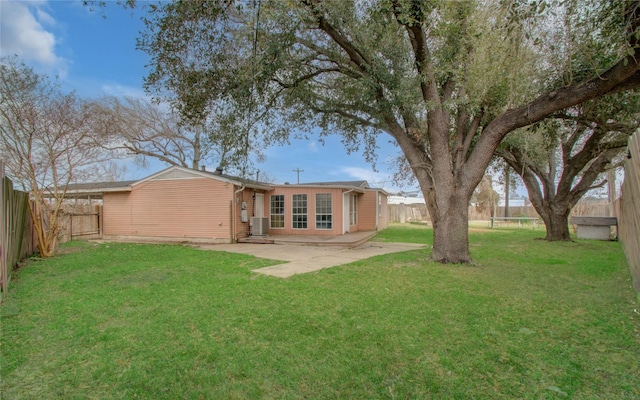 rear view of house with cooling unit, a patio, and a lawn