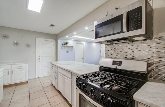 kitchen featuring light tile patterned floors, decorative backsplash, stainless steel appliances, and white cabinets