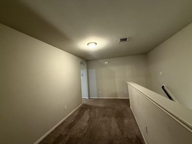 corridor featuring dark colored carpet