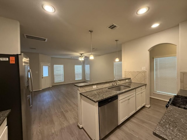 kitchen featuring appliances with stainless steel finishes, pendant lighting, sink, dark stone countertops, and white cabinets