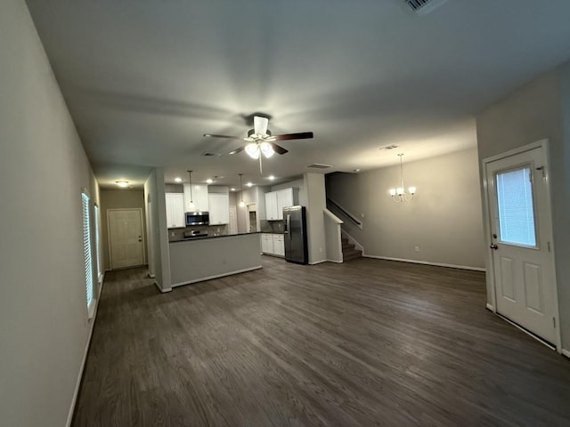 unfurnished living room with ceiling fan with notable chandelier and dark hardwood / wood-style flooring