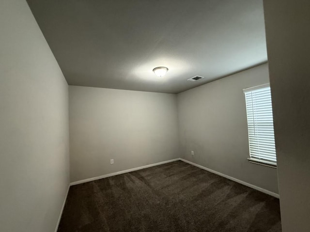 unfurnished room with dark carpet