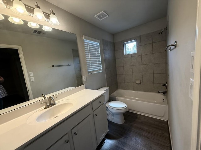 full bathroom with vanity, wood-type flooring, tiled shower / bath, and toilet