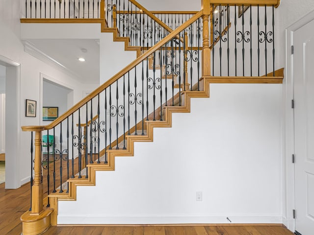 stairs with hardwood / wood-style floors and crown molding