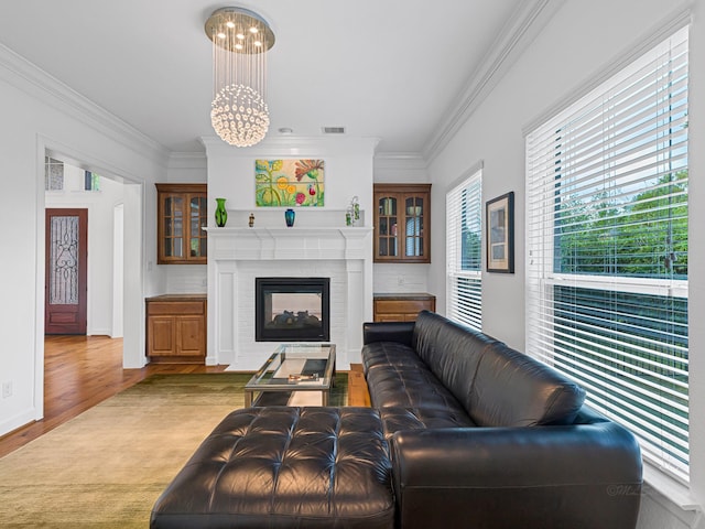 living room with a notable chandelier, crown molding, a fireplace, and hardwood / wood-style floors