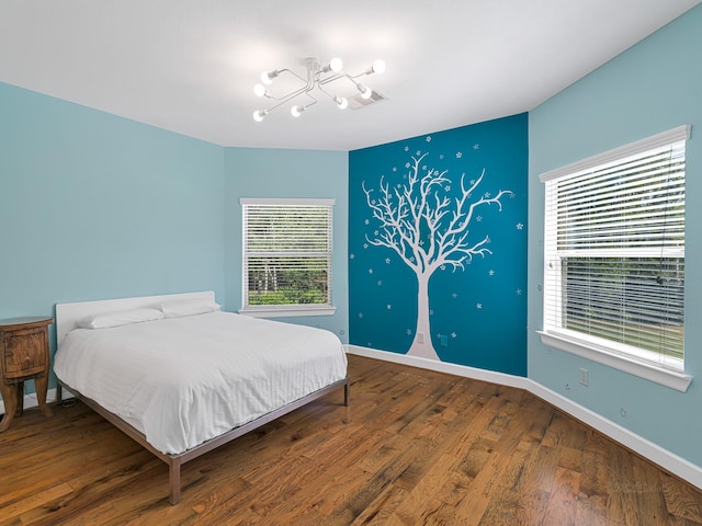 bedroom featuring an inviting chandelier and hardwood / wood-style floors