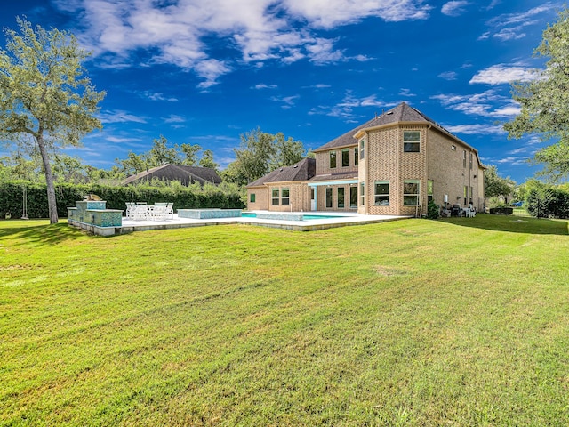 rear view of house with a fenced in pool and a lawn