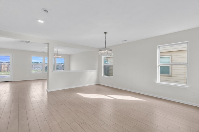 unfurnished room with a chandelier and light wood-type flooring