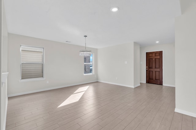 unfurnished room featuring an inviting chandelier and light hardwood / wood-style floors