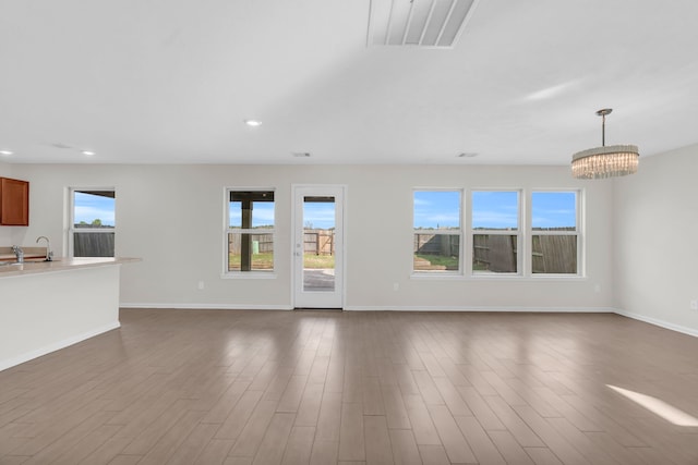 unfurnished living room with sink, a chandelier, and dark hardwood / wood-style flooring