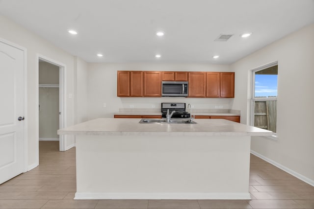 kitchen with stainless steel appliances, sink, and a center island with sink