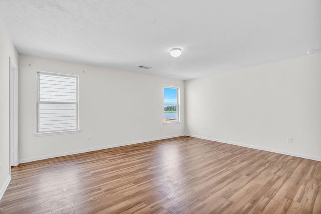 spare room featuring light hardwood / wood-style flooring and a textured ceiling