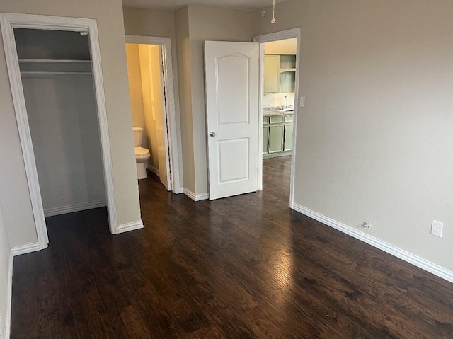 unfurnished bedroom with a closet, sink, and dark hardwood / wood-style floors