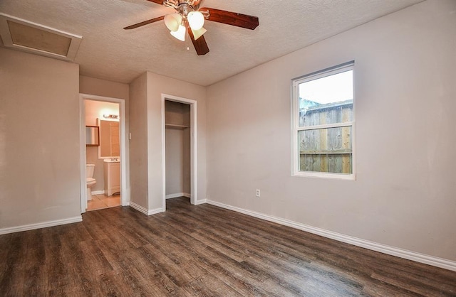 unfurnished bedroom featuring a closet, dark hardwood / wood-style floors, ensuite bath, and a textured ceiling