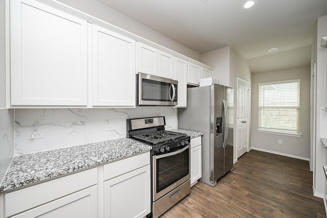 kitchen featuring appliances with stainless steel finishes, white cabinetry, backsplash, light stone counters, and dark hardwood / wood-style flooring