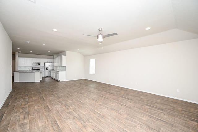 unfurnished living room with vaulted ceiling, sink, hardwood / wood-style floors, and ceiling fan