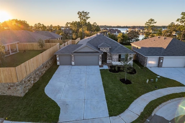 view of front of house with a yard, a garage, and a water view