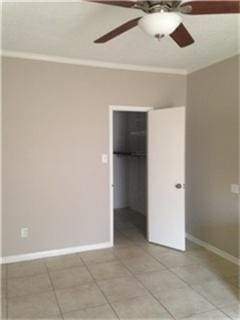 unfurnished bedroom featuring ornamental molding, a spacious closet, light tile patterned floors, and a closet