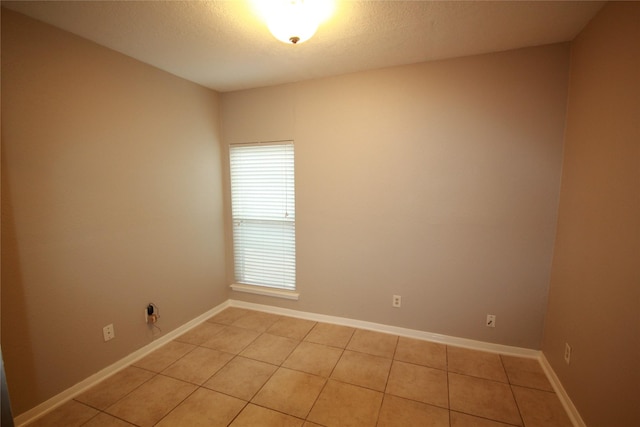 tiled empty room featuring a textured ceiling