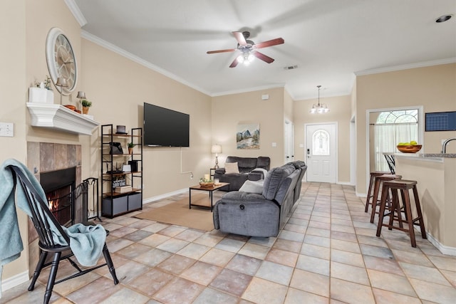 living room with light tile patterned floors, ceiling fan with notable chandelier, ornamental molding, and a tile fireplace