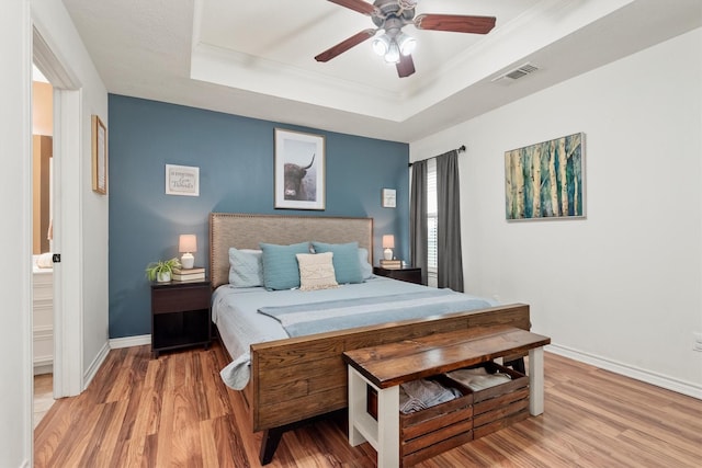 bedroom with hardwood / wood-style floors, a tray ceiling, and ornamental molding