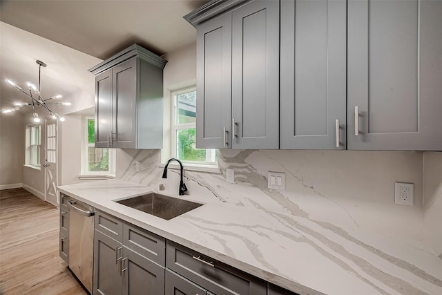 kitchen featuring dishwasher, sink, decorative backsplash, light hardwood / wood-style floors, and light stone counters