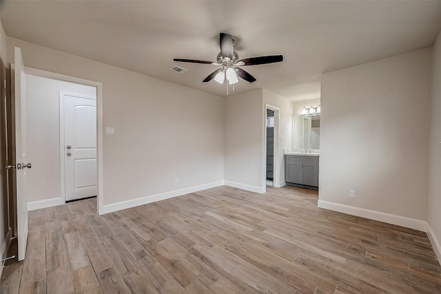 unfurnished room with ceiling fan, sink, and light wood-type flooring