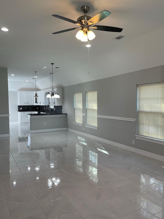 unfurnished living room featuring ceiling fan with notable chandelier