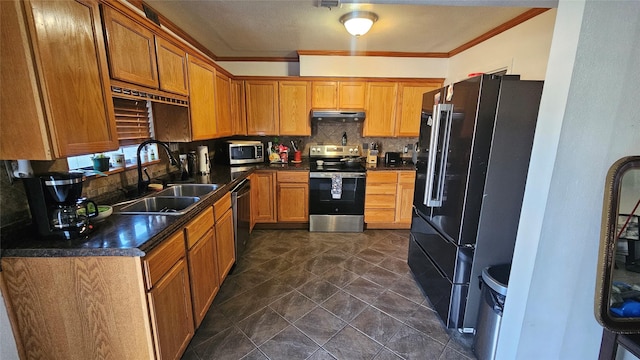 kitchen featuring under cabinet range hood, a sink, appliances with stainless steel finishes, backsplash, and dark countertops