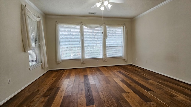 empty room with dark wood-style floors, a wealth of natural light, visible vents, and crown molding