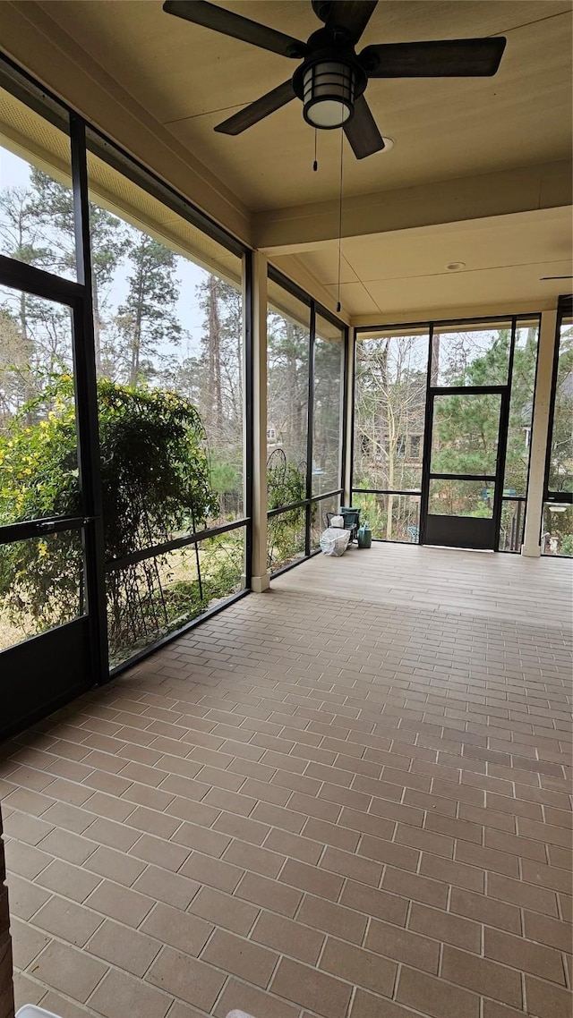 unfurnished sunroom featuring ceiling fan