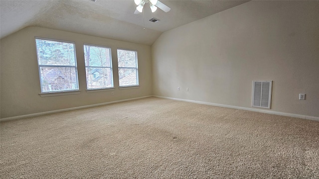 spare room featuring carpet floors, visible vents, and vaulted ceiling