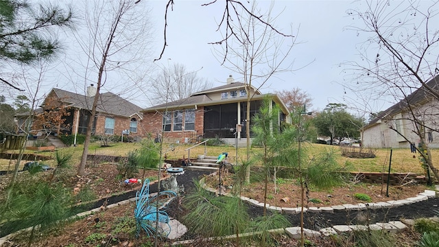 rear view of house featuring a sunroom and brick siding