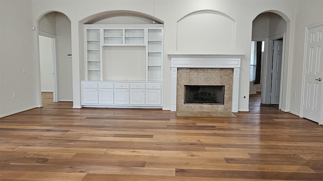 unfurnished living room featuring a fireplace, baseboards, and wood finished floors