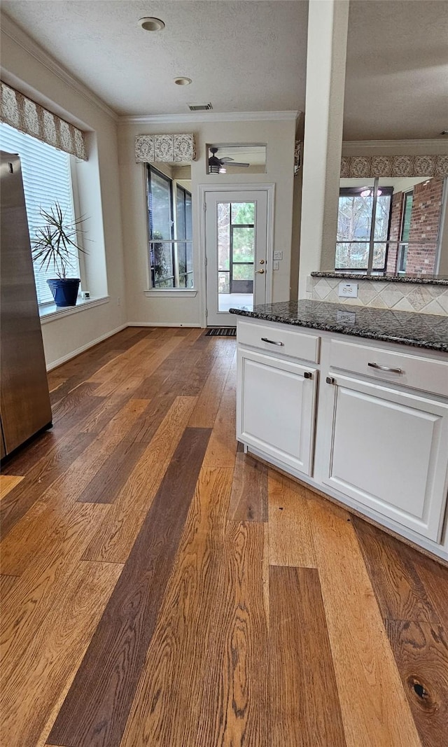 kitchen with light wood finished floors, crown molding, white cabinetry, and dark stone countertops