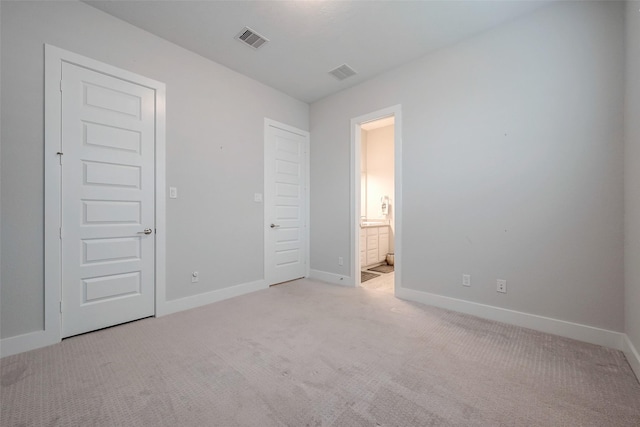 unfurnished bedroom featuring ensuite bath and light colored carpet