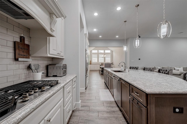 kitchen featuring stainless steel appliances, white cabinetry, a kitchen island with sink, and sink