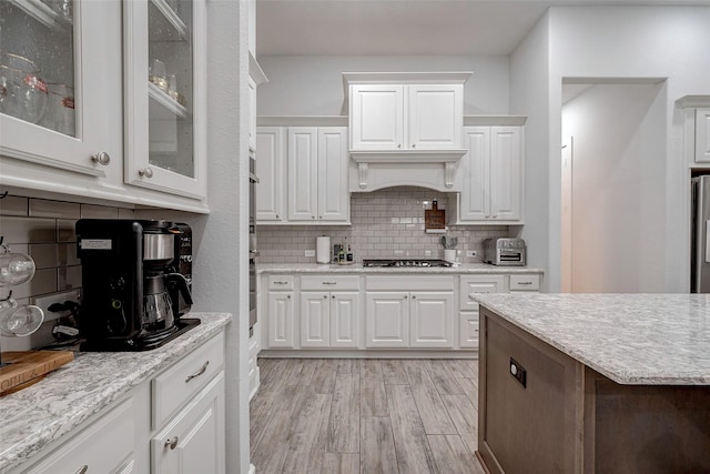 kitchen featuring white cabinetry, light hardwood / wood-style flooring, and decorative backsplash