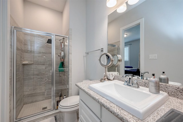 bathroom featuring vanity, toilet, and a shower with shower door