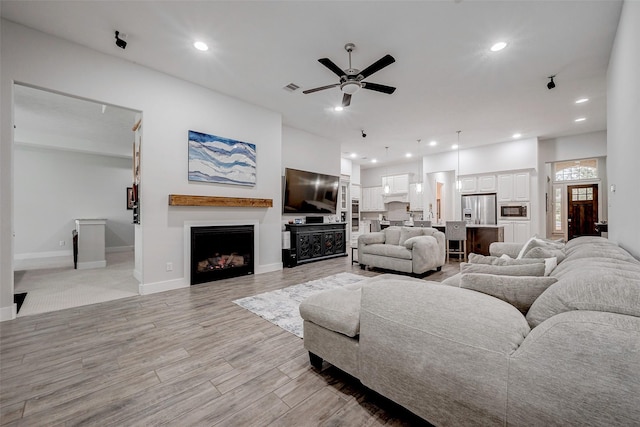 living room with ceiling fan and light hardwood / wood-style floors