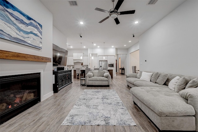 living room with ceiling fan and light hardwood / wood-style floors