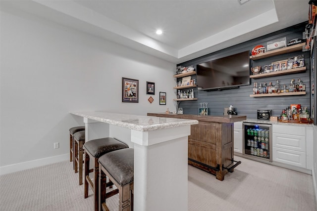 bar with a raised ceiling, white cabinetry, light carpet, and wine cooler