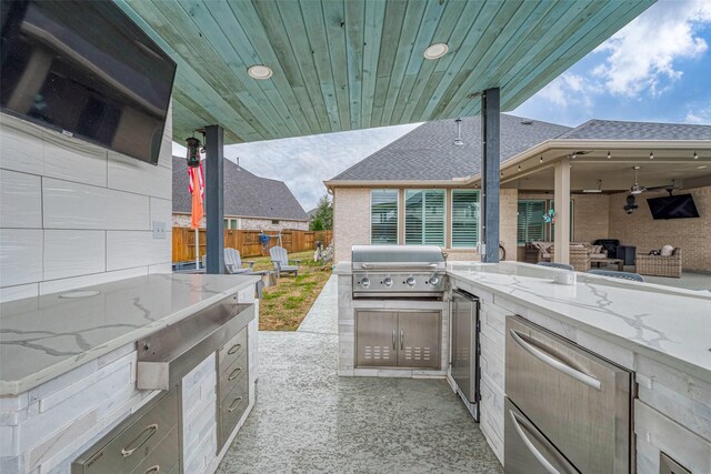 view of patio featuring a grill, ceiling fan, and an outdoor kitchen