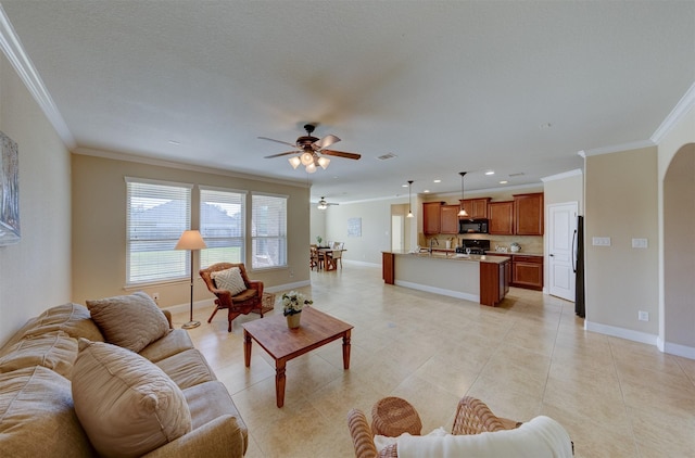 living area featuring arched walkways, ornamental molding, light tile patterned floors, and baseboards