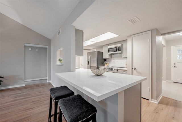 kitchen featuring a breakfast bar, white cabinetry, light wood-type flooring, appliances with stainless steel finishes, and kitchen peninsula