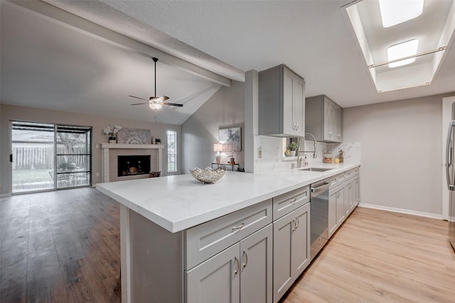 kitchen with sink, gray cabinets, dishwasher, plenty of natural light, and lofted ceiling with beams