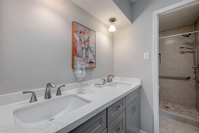 bathroom with vanity, a textured ceiling, and tiled shower