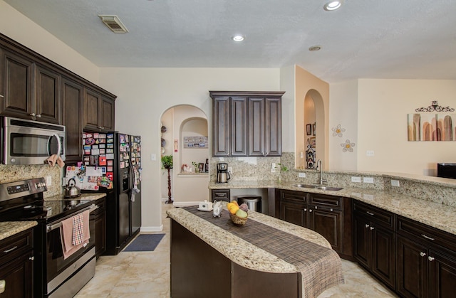 kitchen with appliances with stainless steel finishes, sink, and dark brown cabinets